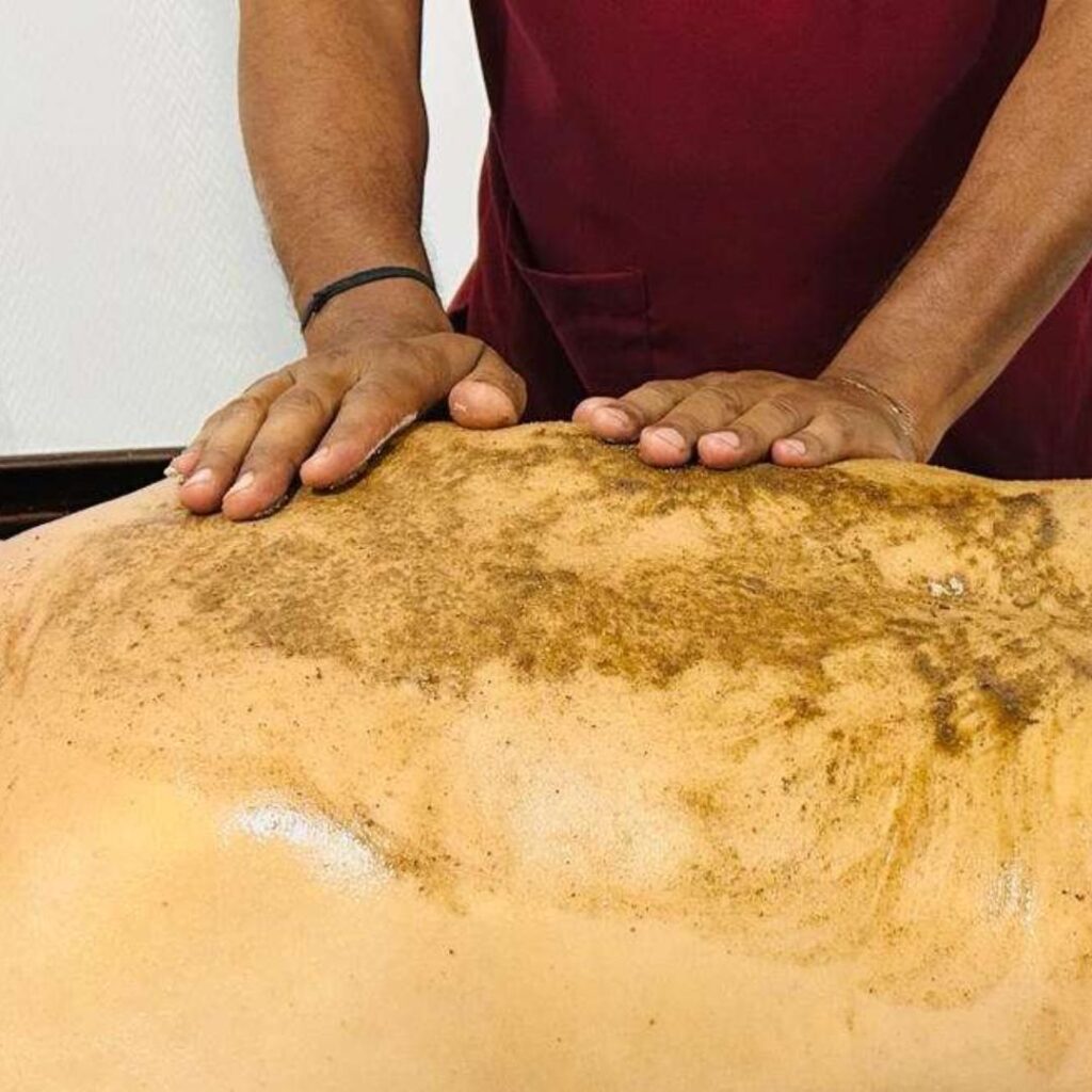 Application of herbal paste and powders using upward strokes in body scrub massage procedure